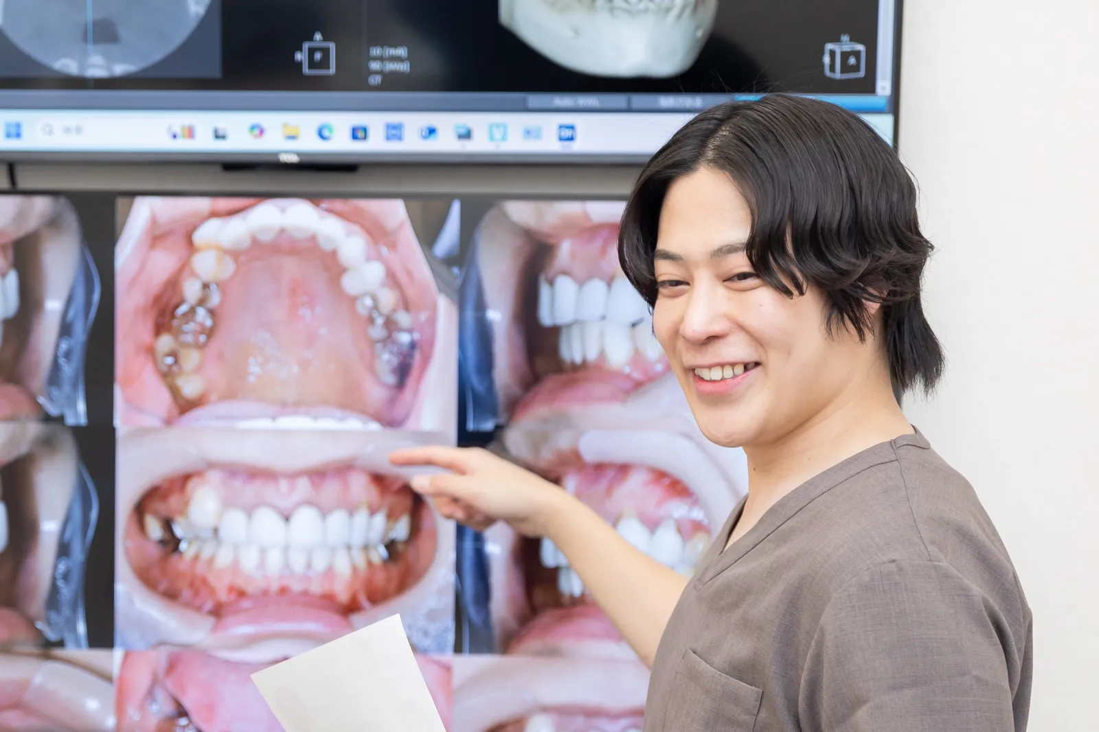 モニターの口腔内写真を指さしながら説明する院長